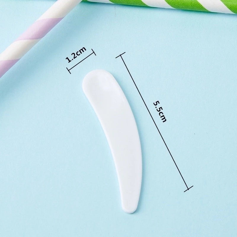White plastic cosmetic spatula with size measurements on a light blue background